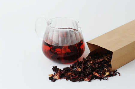 Dried petals pomegranate flowers tea is brewed in a glass teapot. Beautiful ruby infusion. white background. Flower drink, healthy food conceptの写真素材