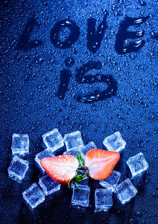 still life. strawberries, ice and the inscription "love it" on a dark background with drops of waterの写真素材