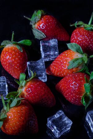 simple still life. Beautiful strawberries and pieces of ice on a dark backgroundの写真素材
