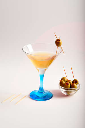 Still life. Glass with martini, light olives with red caviar inside on a light background.の写真素材