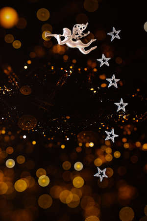 New Year card with a place for your words. Flying angel and silver stars on a creative dark background with evening lights.の写真素材
