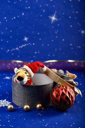 New Year card. The symbol of the new year tiger in the form of a toy, a gift box and Christmas tree decorations on a blue backgroundの写真素材