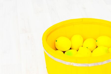 lemons in a large yellow wooden basinの写真素材
