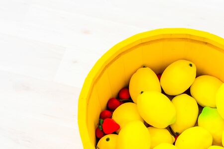 lemons in a large yellow wooden basinの写真素材