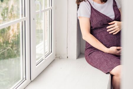 pregnant woman in a dark dress in the interior of a light roomの写真素材