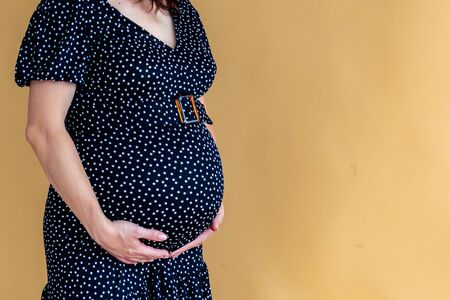 pregnant woman in a dark dress in the interior of a light roomの写真素材