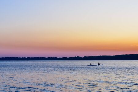 sunset on the big river, surfers in the evening on the calm waterの写真素材
