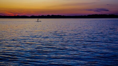 sunset on the big river, surfers in the evening on the calm waterの写真素材