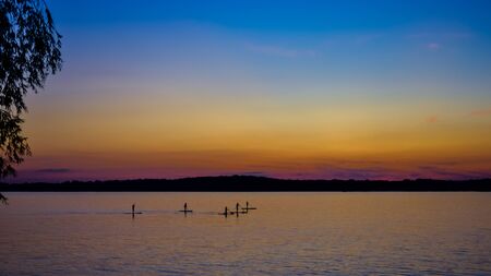 sunset on the big river, surfers in the evening on the calm waterの写真素材