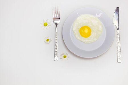 scrambled eggs on a white plate and a bright white table with additionsの写真素材
