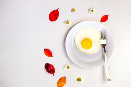 scrambled eggs on a white plate and a bright white table with additionsの写真素材