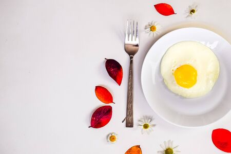 scrambled eggs on a white plate and a bright white table with additionsの写真素材