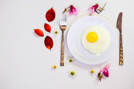 scrambled eggs on a white plate and a bright white table with additionsの写真素材