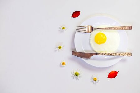 scrambled eggs on a white plate and a bright white table with additionsの写真素材