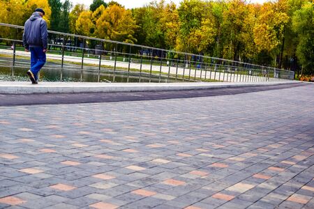 people walk along the pond on a cloudy autumn dayの写真素材