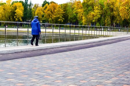 people walk along the pond on a cloudy autumn dayの写真素材