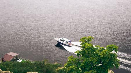 small boat moving on the water on a cloudy spring or summer dayの写真素材