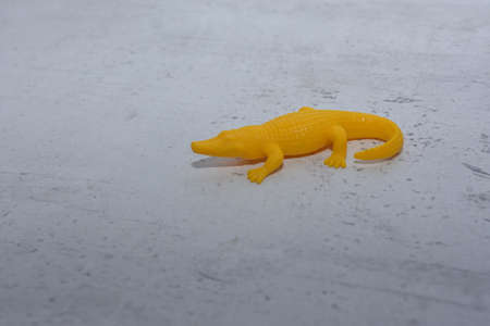 bright yellow toy crocodile in an unusual situationの写真素材