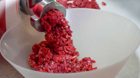 raw meat on the cutting table, cooking minced meat in the kitchen with a meat grinder