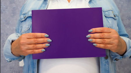 woman holds a paper sheet in her hands with a bright manicureの写真素材