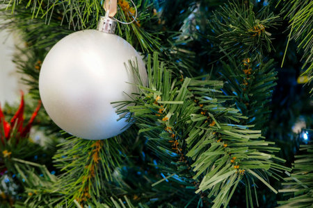 White christmas ball hanging on a green christmas tree with blurred backgroundの写真素材
