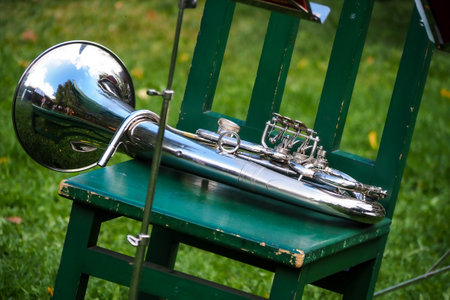 Closeup of a brass instrument on a green chair in a park