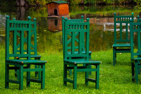 Wooden green chairs in the park on the bank of the lakeの写真素材
