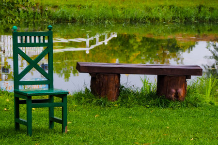 Wooden bench and chair in the park with reflection of the lakeの写真素材