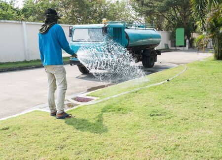 Gardener watering the garden on sunny dayの写真素材