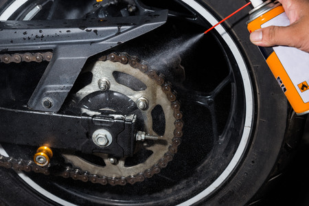 Cleaning and oiling a motorcycle chain and gear with oil Sprayの写真素材