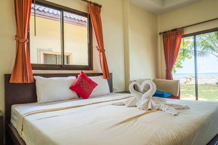 Tropical bedroom interior with double bed and seascape view.