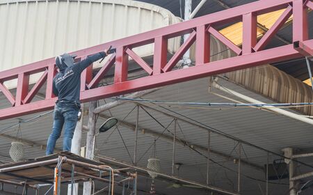 worker welding metal with sparks at roofの写真素材
