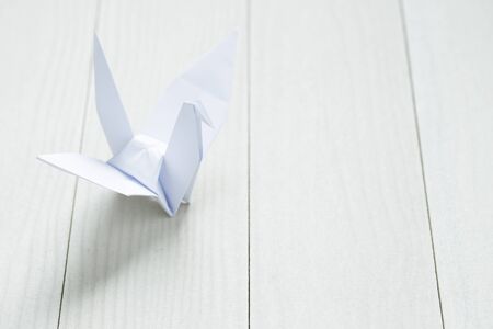 Origami paper bird on white tableの写真素材