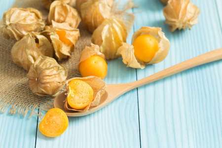 Cape gooseberry in wooden spoon on blue wooden tableの写真素材