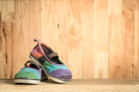 Children's shoes lay on a wooden table.
