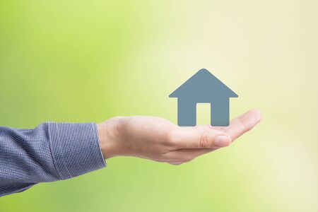 Male hand holding house on green backgroundの写真素材