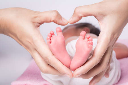baby feet in mother hands - hearth shapeの写真素材