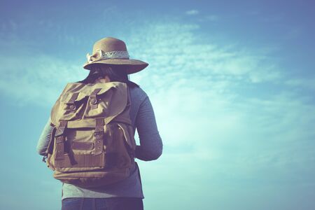 Hipster young woman with backpack enjoying. Tourist traveler on blue sky background,Retro filter...