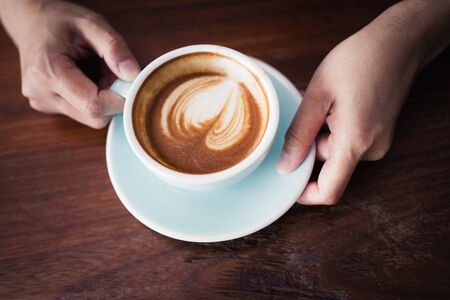 Woman's hand holding a cup of coffee,A cup of coffee in the hand of an Asian woman top view.の写真素材