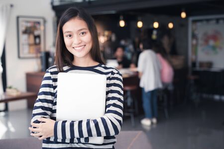 New Generation asian woman smiling holding a notebook in a coffee shopの写真素材
