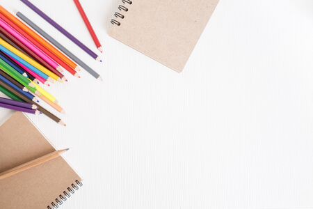 White wood desk with a notebook and crayon,top view and copyspace