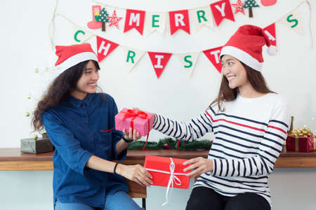 Beautiful young female is celebrating at home,woman is giving his girlfriend a gift box,chrismas conceptの写真素材