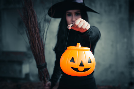 The witch in hand has Halloween pumpkin on dark background, Halloween day conceptの写真素材