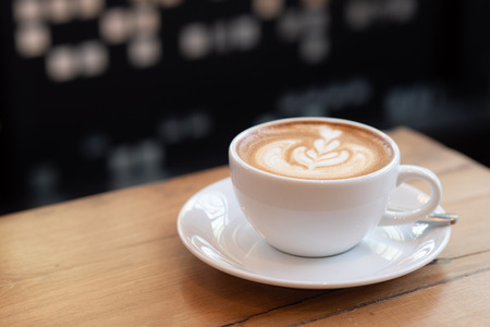 coffee latte in a white cup on wooden table in coffee shop.の写真素材