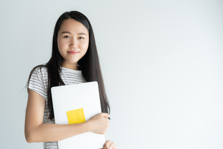 Asian woman is holding laptop on white background . Portrait a young girl so cute when smiling and happy.の写真素材