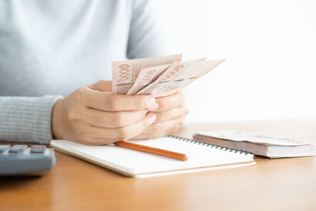Close up of asian woman with calculator counting money.Woman calculate the spending at home.の写真素材