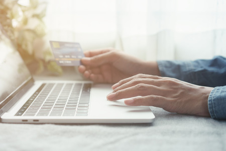 Close up hand of businessmen are buying online with a credit card. Men are using laptop and doing...