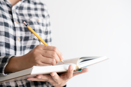 close up on hand writing paper notebook. On young woman left hand holding notebook and right hand writing diary.の写真素材