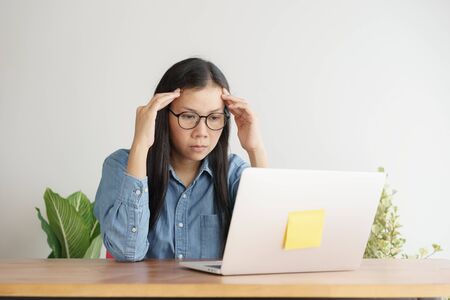 Asian women stressful working with a computer for a long time, Office syndrome conceptの写真素材