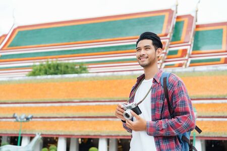 Asian man tourist walking talk smart phone and smile at Wat Suthat Thepwararam Ratchaworawihan Bangkok, Thailand in the summer time, Solo travel and backpacker conceptの写真素材